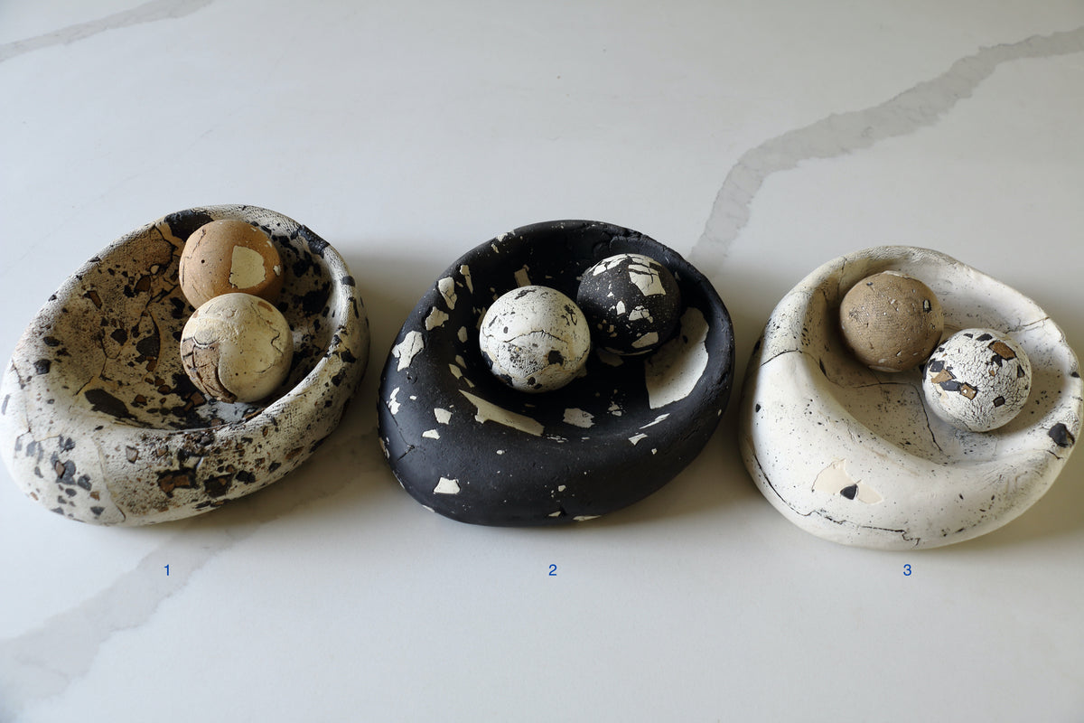Three handmade ceramic bird nests displayed side-by-side on a light marble surface, numbered 1, 2, and 3. Each ceramic nest contains two decorative eggs with speckled patterns.